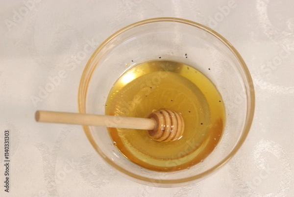 Fototapeta Honey bee in a bowl of honey.A bowl with honey and a dipper to take honey
