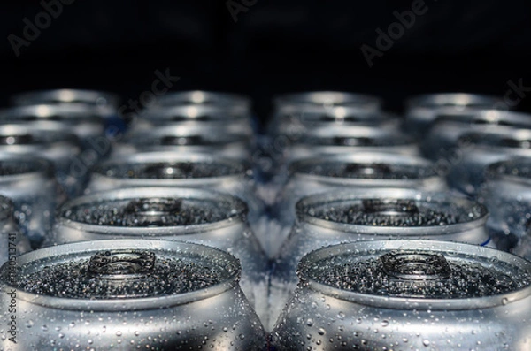 Fototapeta Selective focus close-up of rows of wet drink cans receding into the distance