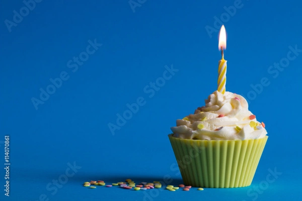 Obraz yellow birthday cupcake with burning candle and blue background