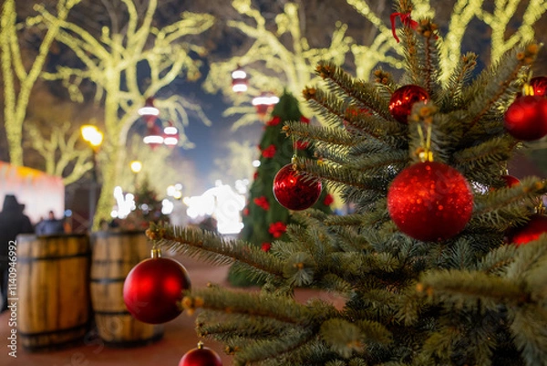 Fototapeta Festive Christmas tree with red ornaments in a holiday market setting.