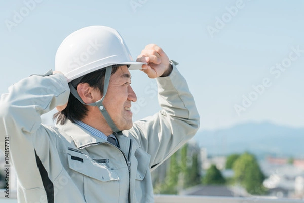 Fototapeta 青空の中に立つ作業服を着た作業員（建設・建築・設計・不動産・土木・工事・現場監督・運送）
