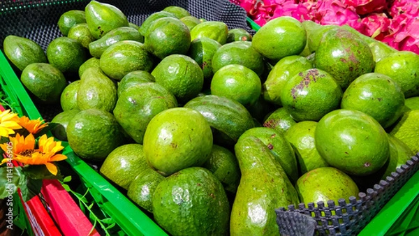 Obraz A pile of fresh avocados, in a green basket in a supermarket