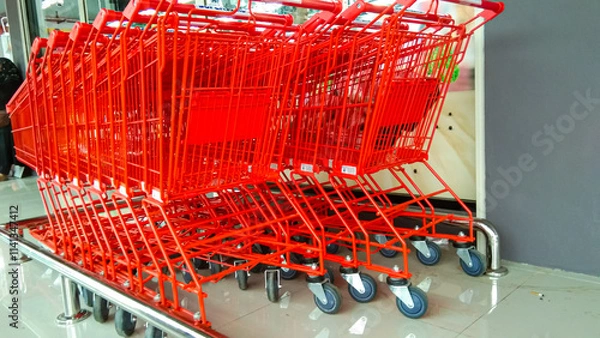 Obraz Red shopping trolleys are neatly lined up in the corner of a supermarket.