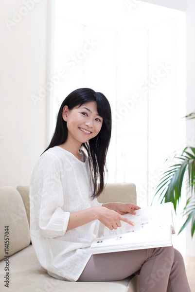 Fototapeta 通販カタログを見る若い女性