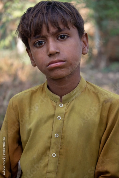 Obraz Candid Portrait of a Young Boy in Yellow Traditional Clothing with a Thoughtful Expression Outdoors