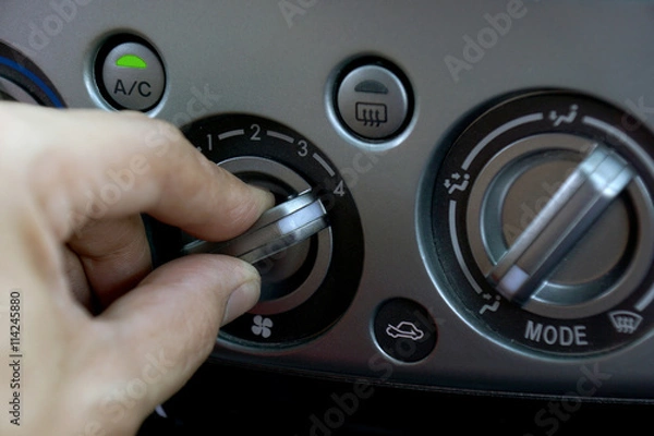 Fototapeta Left hand adjusting a fan level control knob of the car's air conditioning system.