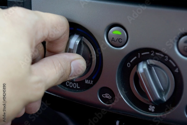 Fototapeta Left hand adjusting a temperature control knob of the car's air conditioning system.