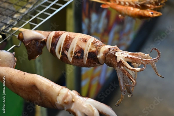 Fototapeta Grilled squids being displayed on grill grid	