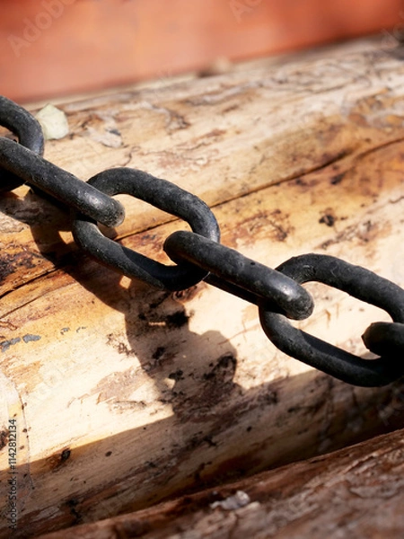 Fototapeta close-up black rusty chain on wood