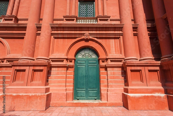 Fototapeta Big red house with columns and old wooden door in front.