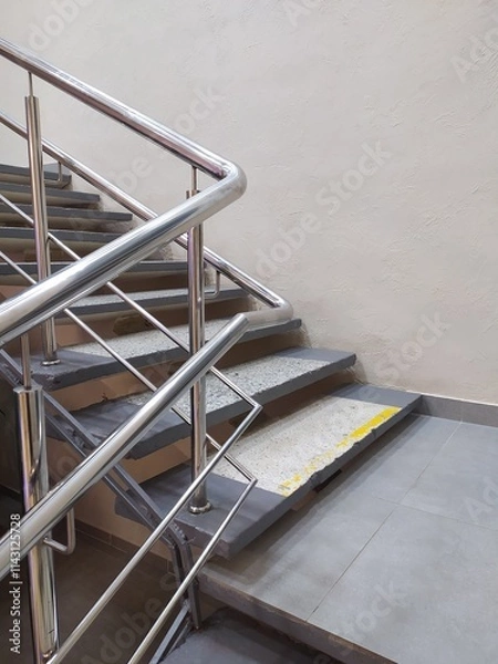 Fototapeta Metal safety railings along the stairs in building. The railings protect a person from falling on the steps and serve as support if necessary.