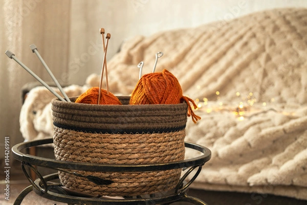 Fototapeta Basket full of red thread spools against sofa and warm blanket. Creative and warm atmosphere
