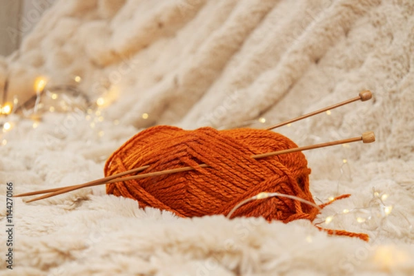 Fototapeta Red thread spool and wooden knitting needles on warm light brown blanket