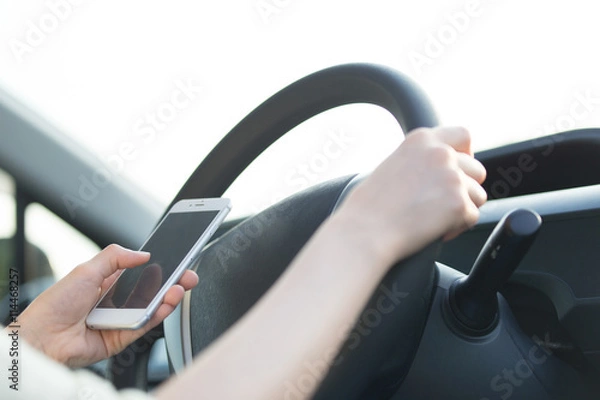 Fototapeta 運転しながらスマホを触る女性