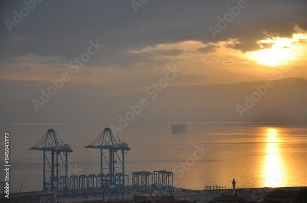 Fototapeta Rijeka city new crains for harbour and containers. Modern Crain that moves with to remote. Most modern Crain in Europe. Sunset over Rijeka harbour. Croatia