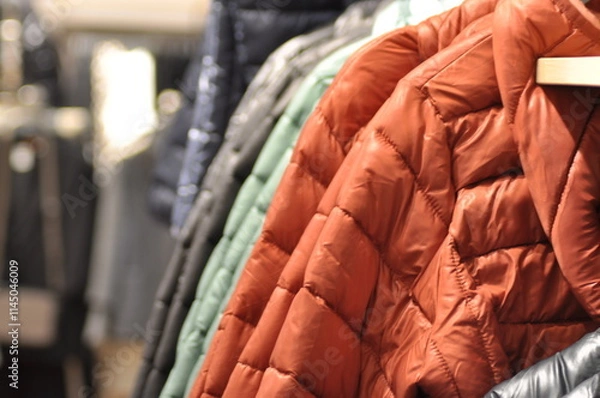 Fototapeta Colorful Jackets and Coats Neatly Hung on a Rack in a Fashion Store. Concept of Winter Apparel, Textile Variety, Retail Display, clothes shop, and Clothing Organization. Banner