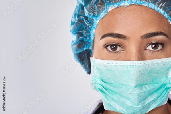 Obraz Mixed race female surgeon in surgical mask with copy space