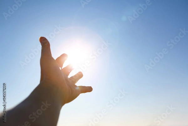 Obraz New Year's sunrise, the bright light shining through the fingers and hands stretched out toward the rising sun, the concept of hope and wishes for the future
