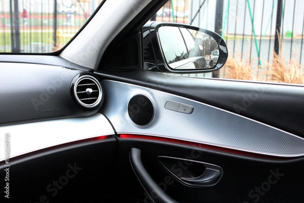 Fototapeta Car interior with view of air conditioner vent and side view mirror. Front Airbag. Vent for air flow in passenger side. Sound speaker in a modern car door panel. Close up car speaker on car door panel