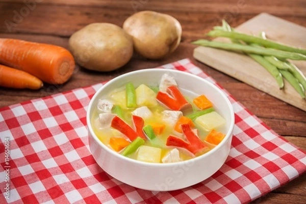 Fototapeta Bowl of vegetables soup with chili, cube pork, carrot and green pumpkin on the table in restaurant