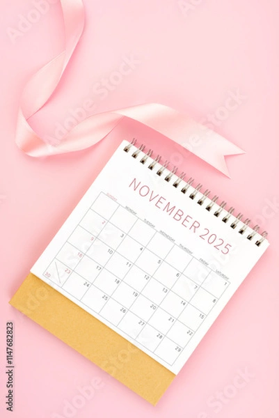 Obraz November 2025 desk calendar with pink ribbon.