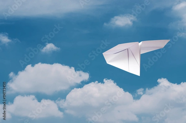 Fototapeta Paper plane flying over clouds with blue sky.