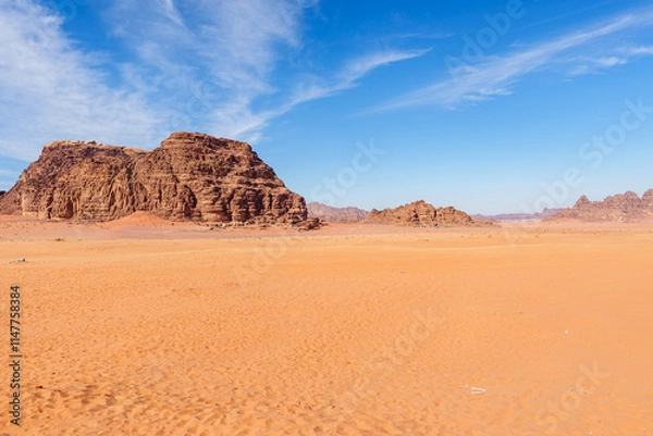 Fototapeta Scenic view of Wadi Rum Desert in Jordan. Landscape with Rocky Formation Under Blue Sky and Wispy Clouds..