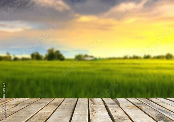 Fototapeta Wooden table top on blur rice field background in daytime.Harvest rice or whole wheat.For montage product display or design key visual layout.View of copy space.