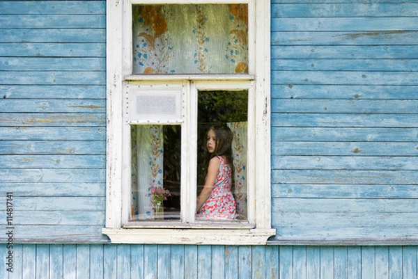 Obraz Sad bored little girl sitting on the sill and looking out the country house window. Outside view