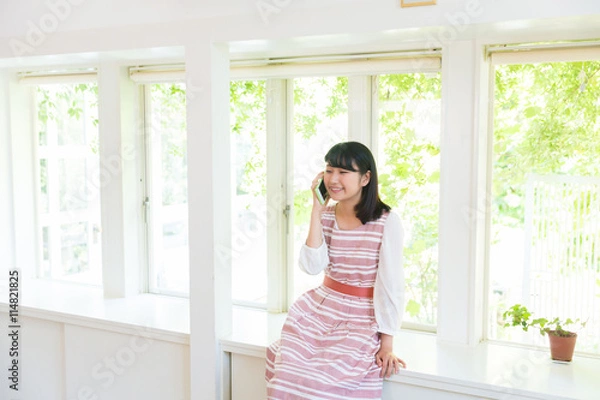 Fototapeta 部屋で電話をする女性