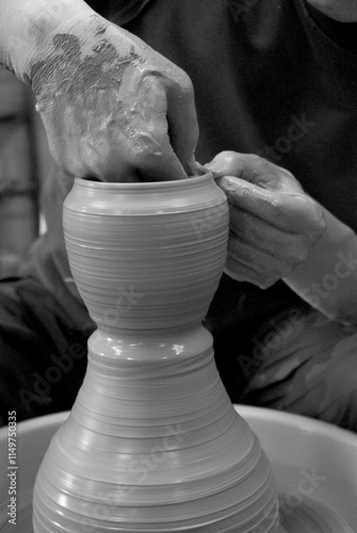 Fototapeta Hands are crafting pottery on a wheel, shaping wet clay into a tall form. The process reflects Japan’s rich tradition of ceramic art, blending skill and care in every movement.