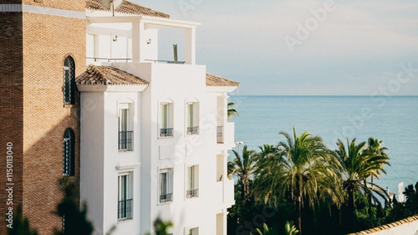 Fototapeta A charming seaside building, gracefully nestled among tropical palm trees, evokes a sense of tranquility and luxury