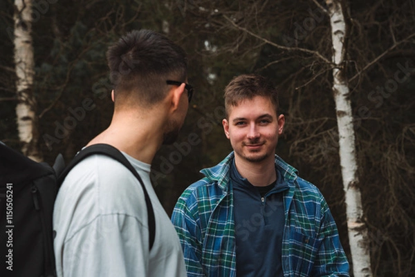 Fototapeta Two men are standing together in the lush woods talking to one another