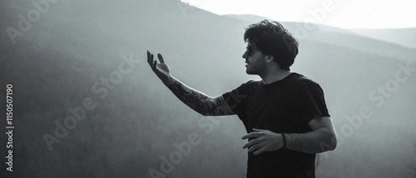 Fototapeta A man in a black shirt stands before a mountain in a photo
