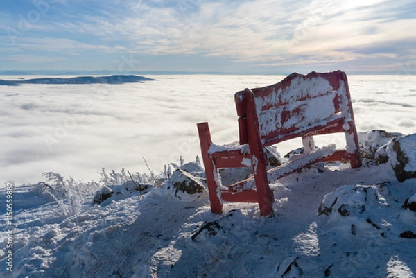 Obraz An old red bench on top of a mountain with a view of the mountain peaks above the clouds.