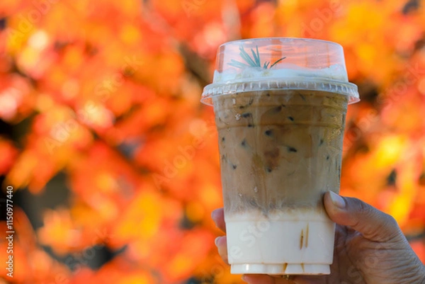 Obraz Hand holding Iced Coffee with autumn background and maple leaves and bokeh