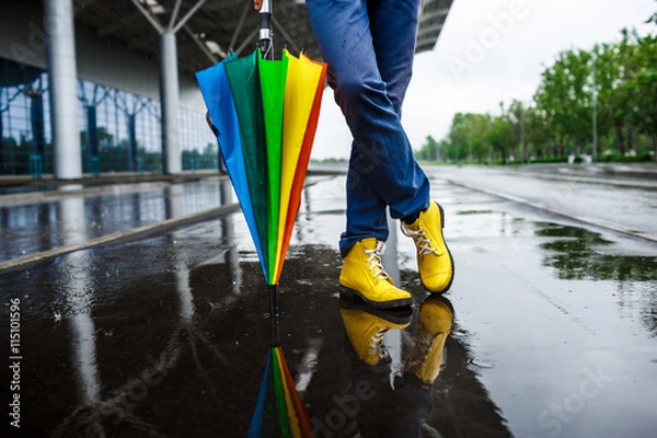 Obraz Picture of  young businessman's yellow shoes and motley umbrella in rainy street