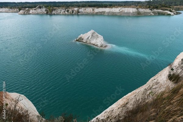 Fototapeta A chalk quarry with blue or turquoise water, steep cliffs and a rocky island