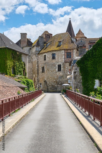 Fototapeta View at the medieval village of Carennac in Lot Occitanie Southern France from the bridge under a blue sky with clouds in summer. Image withe copy space
