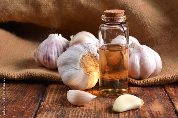 Obraz Raw and ripe garlic with garlic oil in a glass bottle on a wooden table. Natural remedy and organic concept. Close-up, garlic background