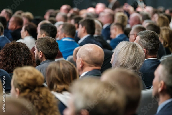 Obraz Large audience attentively listening to speaker during professional conference in modern meeting hall.