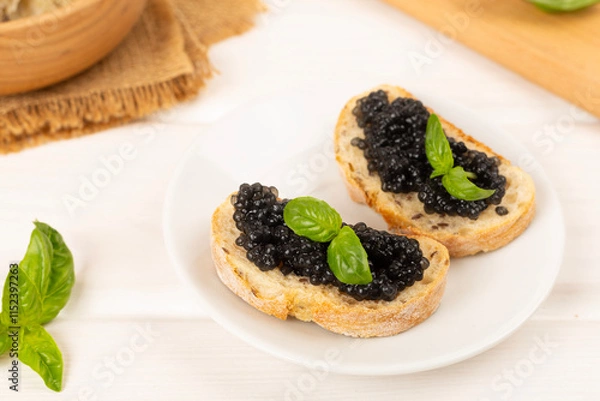 Fototapeta Bread slice with black caviar served on on wooden table