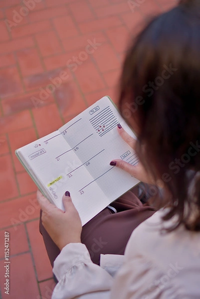 Obraz  A close-up of a woman jotting down her yearly goals in a beautifully decorated journal. The page features headings like "Goals 2025" and creative accents like hand-drawn illustrations. 