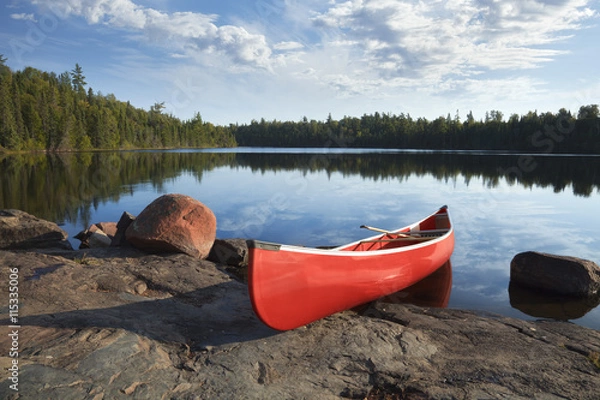 Fototapeta Czerwony kajak na skalistym brzegu Calm Lake z sosnami