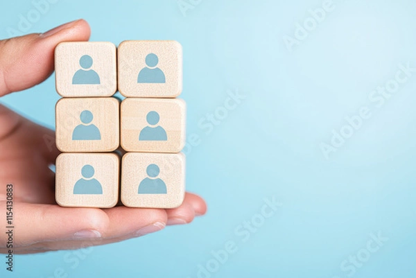 Fototapeta Hand holding wooden blocks with human icons, symbolizing teamwork and collaboration in a modern workplace.