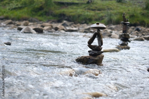 Fototapeta Two figures made of river stones in the middle of the stream.