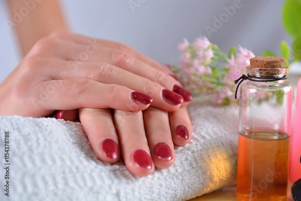 Fototapeta Close-up of woman’s hands with red nail polish on a towel in a beauty salon. Manicure and beauty concept