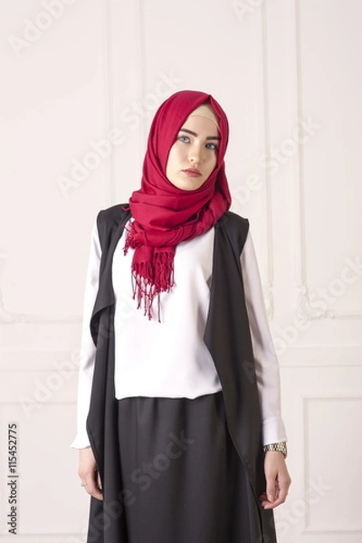 Fototapeta studio portrait of young woman Caucasian appearance in the modern Muslim clothes and a scarf on her head on a light classical background