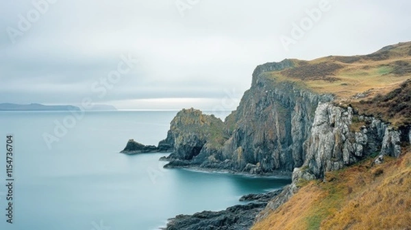 Fototapeta Serene coastal cliffs with calm waters under a cloudy sky.