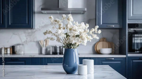 Fototapeta Kitchen in scandinavian style with island table, blue furniture and modern kitchenware. Bright interior with white walls and floor. Vase with flowers on marble countertop.
